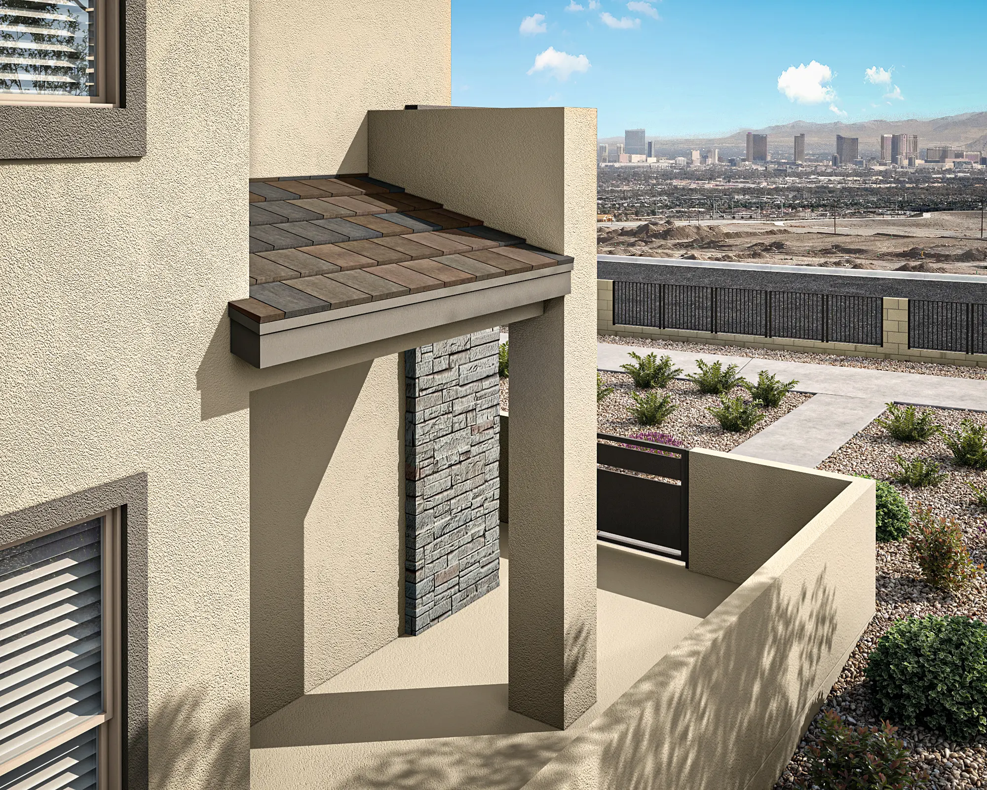 A modern beige house features a stone accent wall, a brown shingle roof overhang, and a small patio area with desert landscaping. In the distance, a city skyline and mountains are visible under a blue sky with clouds.