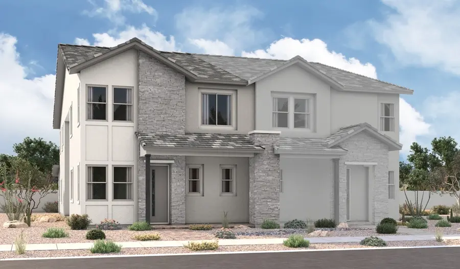 Nina-2-Elevation-B Two-story modern suburban house with a gray tile roof, light stone and stucco exterior, multiple windows, and desert landscaping with rocks and small shrubs under a blue sky with clouds.